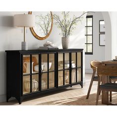 a dining room table with vases on it and a mirror hanging over the sideboard