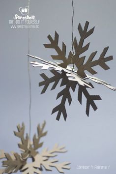 two snowflakes hanging from strings in the air, one is upside down