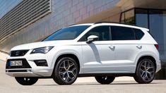 a white suv parked in front of a building with large windows and black rims