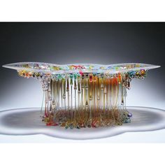 a glass table with lots of colorful beads on it's sides and hanging from the top