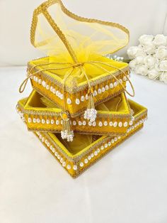 three yellow jewelry boxes with pearls and bows on them are sitting next to each other