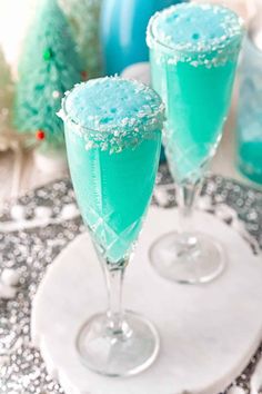 two glasses filled with blue liquid and sprinkles on top of a table