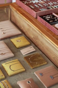 a display case filled with lots of different types of earrings and bracelets on wooden shelves