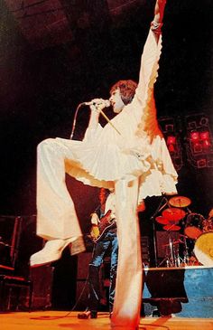 the man is performing on stage with his legs in the air and one leg raised up