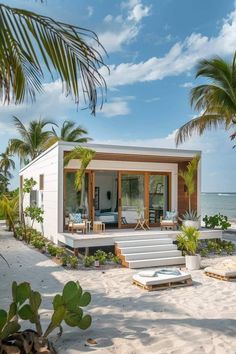 a small house on the beach surrounded by palm trees