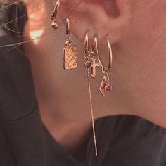 a close up of a person's ear wearing earrings with charms attached to them