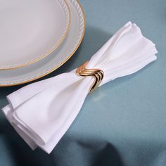 a white napkin with a gold ring on it sitting next to a plate and fork