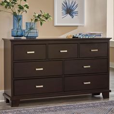 a brown dresser with two vases on top of it next to a blue rug