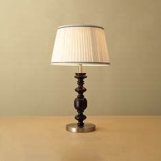 a lamp that is sitting on top of a wooden table next to a white lampshade