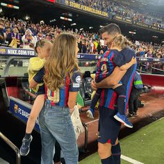 a woman holding a child in her arms at a soccer game