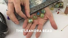 a person is holding some glass beads in their hand and the words the leandra bead above them