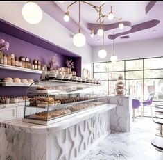 the interior of a bakery with purple walls and white marble counter tops, along with lots of baked goods