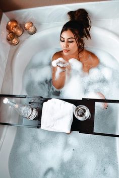 a woman is in the bathtub with soap and shampoo