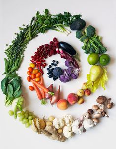 an array of fruits and vegetables arranged in the shape of a circle on a white surface