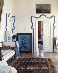 an ornately decorated living room with blue and white accents on the walls, rugs, and paintings