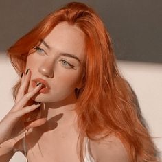 a woman with red hair is holding her finger up to her mouth