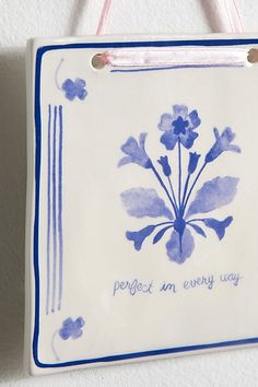 a blue and white ceramic plaque with flowers on it that says, perfect in every way