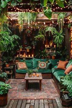 an outdoor living room with green couches and potted plants on the wall, surrounded by string lights