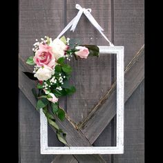 a white frame hanging on the side of a wooden wall with pink and white flowers