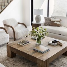 a living room filled with furniture and a wooden coffee table in front of a stair case