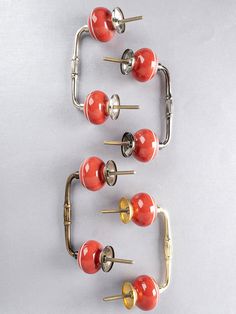 four red and gold knobs are arranged in a row on a white surface,