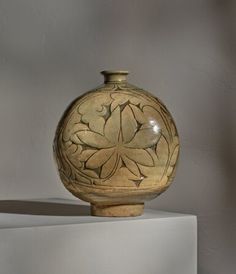 a brown vase sitting on top of a white shelf next to a gray and white wall