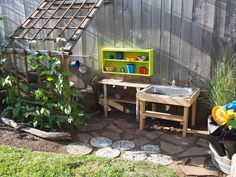 an outdoor play area in the backyard with various toys and accessories on it, including a sink