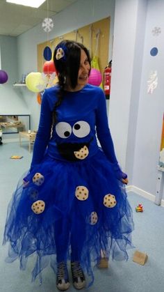 a woman in a blue dress with cookies on her face and eyes, standing next to balloons