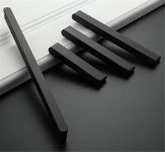 four pieces of black wood sitting on top of a white table next to a window