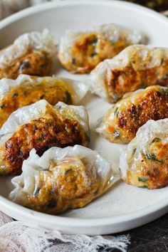 a white plate topped with dumplings covered in cheese and sauce on top of a table