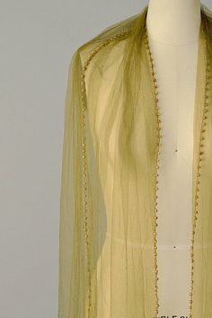 a white mannequin wearing a yellow jacket with beads on it's neck