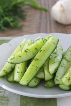 sliced cucumbers on a white plate with herbs