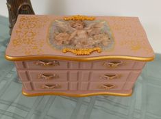 a pink and gold chest with an angel on it