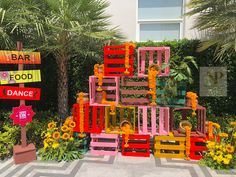 there are many colorful wooden crates in the garden with flowers and signs around them that read, bar food dance