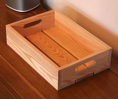 a wooden tray sitting on top of a wooden floor next to a wall and a speaker