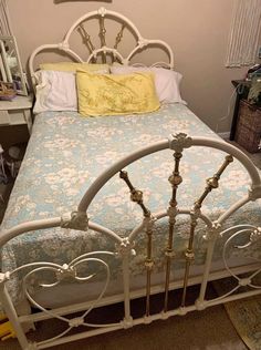 a white metal bed with blue and yellow bedspread