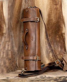 a brown leather bag sitting on top of a wooden table next to a piece of wood