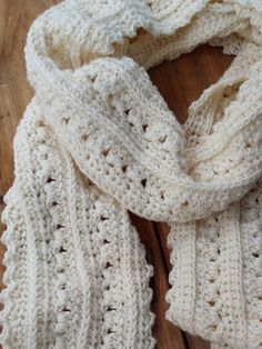 a white knitted scarf sitting on top of a wooden table