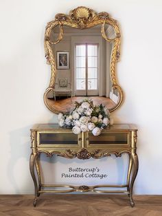 a mirror sitting on top of a wooden table next to a vase filled with flowers