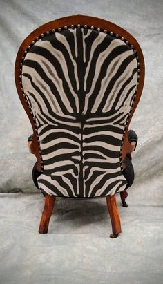 a zebra print chair sitting on top of a white floor next to a gray wall