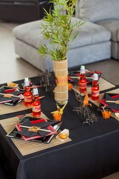 a table topped with bottles and plates covered in paper cranes on top of a black table cloth