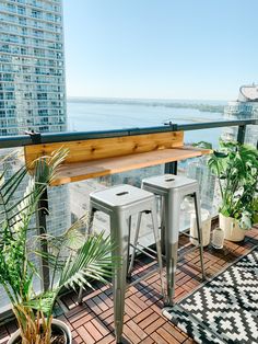 two metal stools sitting on top of a wooden floor next to plants and potted plants