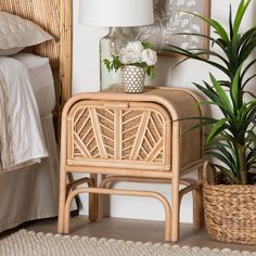 a wicker side table next to a bed with a plant on top of it