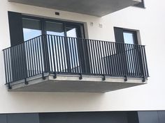 an apartment building with balconies and black shutters on the second story balcony