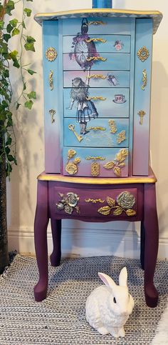 a white rabbit sitting in front of a painted dresser