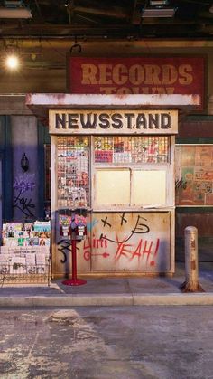 an old news stand with graffiti on the front and side walls, along with other items