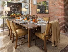 a dining room table set for four with fall decorations on the table and chalkboard in the background