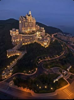 an aerial view of a large building lit up at night with lights on the top