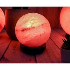 three lit up balls sitting on top of a wooden table next to potted plants