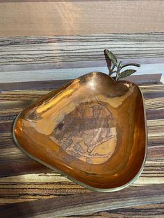 a brown bowl with a plant in it on a wooden table next to a card holder